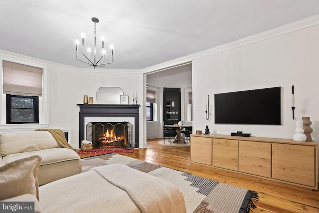 living room featuring ornamental molding, an inviting chandelier, and light hardwood / wood-style floors