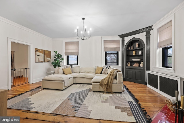 living room featuring hardwood / wood-style floors, a notable chandelier, ornamental molding, radiator heating unit, and built in shelves