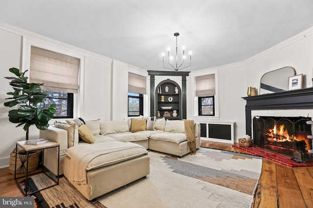 living room with built in shelves, crown molding, hardwood / wood-style flooring, and a notable chandelier