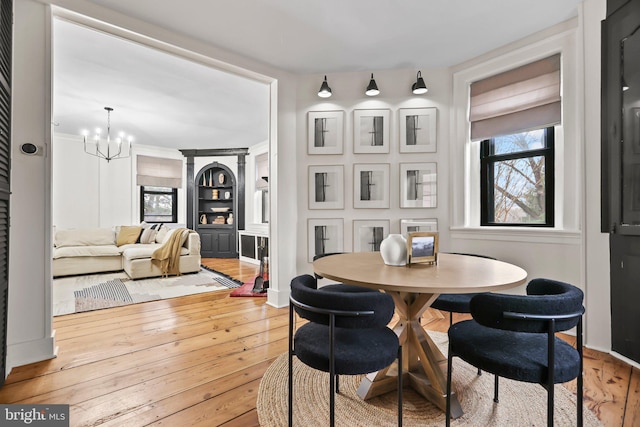 dining area featuring built in shelves, a notable chandelier, and wood-type flooring