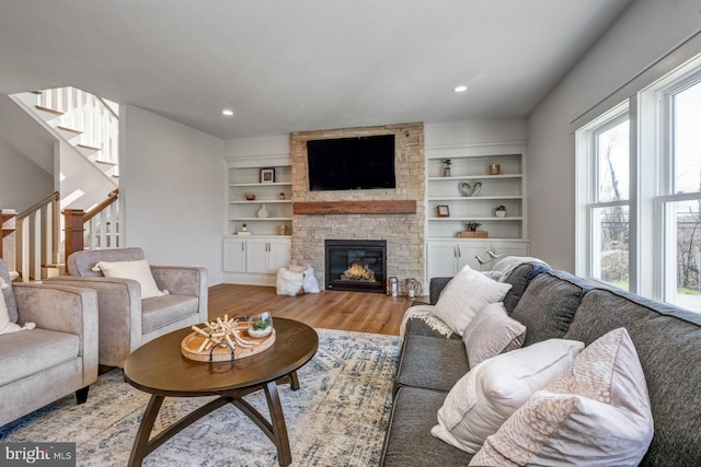 living room featuring a stone fireplace and light hardwood / wood-style flooring