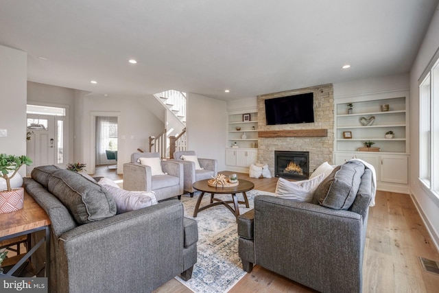 living room with a stone fireplace and light hardwood / wood-style floors