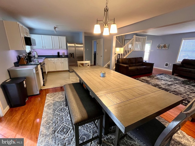 dining space featuring sink, a notable chandelier, and light hardwood / wood-style flooring