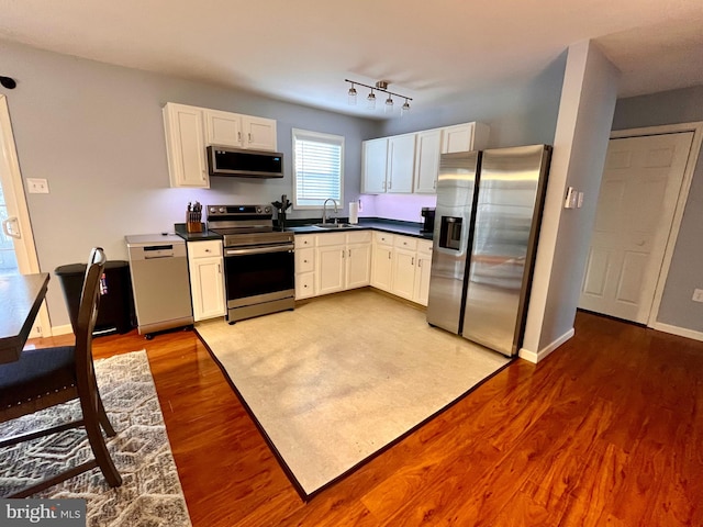 kitchen with white cabinetry, appliances with stainless steel finishes, sink, and light hardwood / wood-style flooring