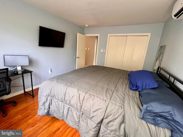 bedroom with wood-type flooring, a closet, and a wall mounted air conditioner