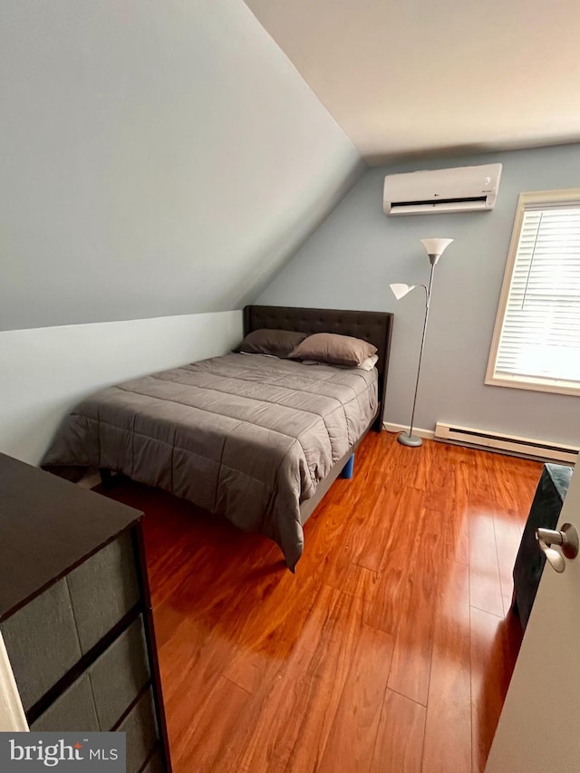 bedroom with a baseboard heating unit, a wall unit AC, wood-type flooring, and lofted ceiling