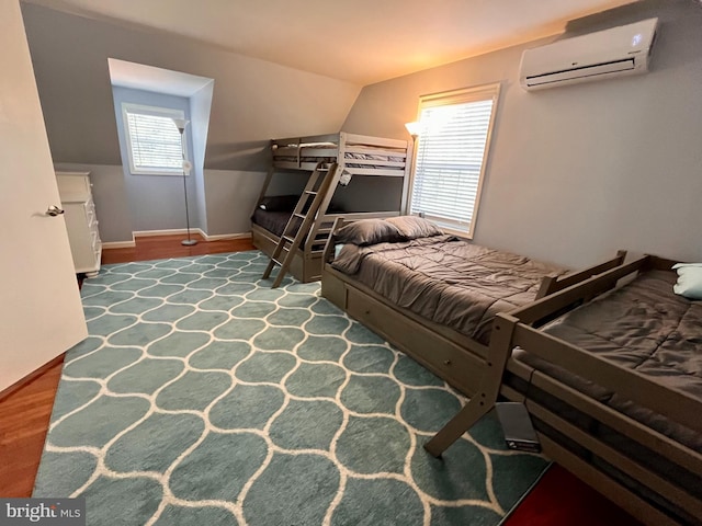 bedroom with a wall mounted AC, wood-type flooring, and vaulted ceiling