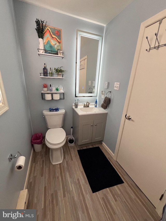 bathroom featuring toilet, vanity, and hardwood / wood-style floors