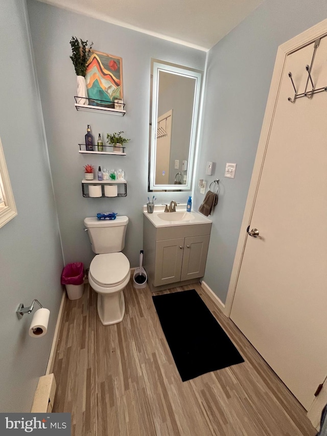 bathroom with toilet, vanity, and hardwood / wood-style flooring