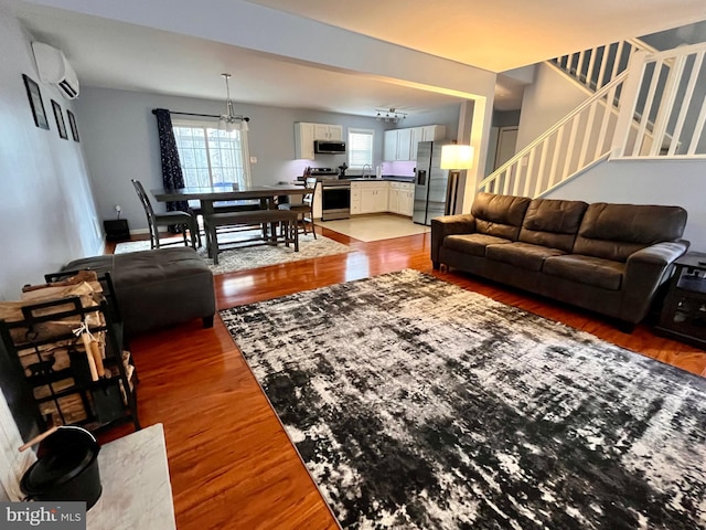 living room featuring a wall mounted AC, hardwood / wood-style flooring, and sink