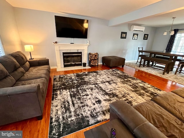 living room featuring beamed ceiling, wood-type flooring, and a wall mounted AC