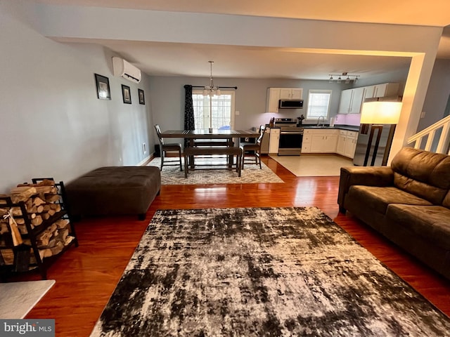 living room featuring an AC wall unit, dark hardwood / wood-style flooring, sink, and a notable chandelier