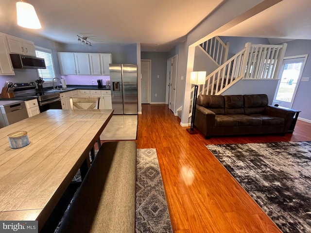 kitchen with stainless steel appliances, a wealth of natural light, white cabinetry, and light hardwood / wood-style flooring