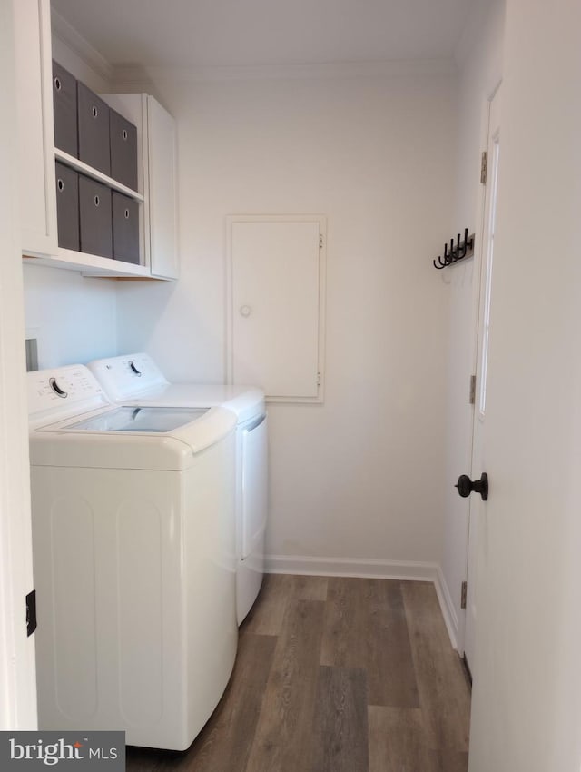 laundry room with cabinets, dark wood-type flooring, washer and clothes dryer, and ornamental molding