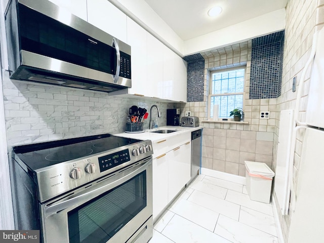 kitchen featuring decorative backsplash, white cabinets, sink, and stainless steel appliances