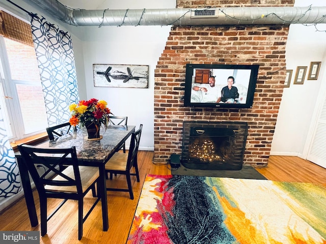 dining area featuring a fireplace and wood-type flooring