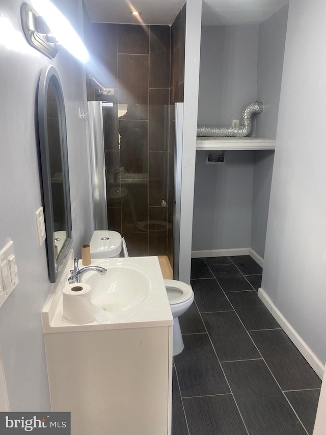 bathroom featuring toilet, vanity, tile patterned floors, and a shower with shower door