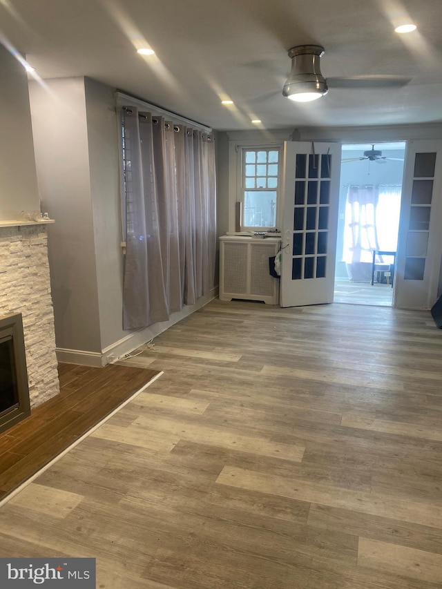 interior space with hardwood / wood-style floors, a stone fireplace, and ceiling fan