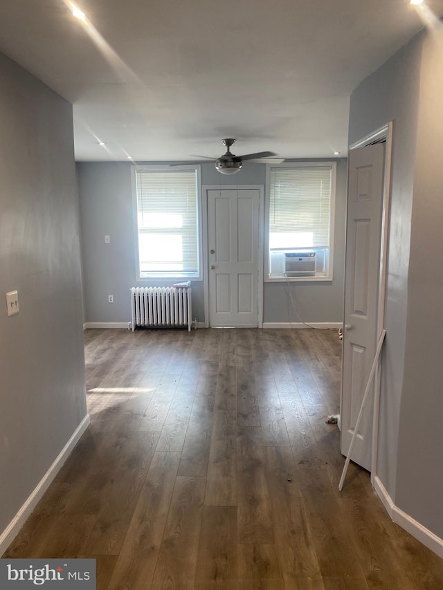 empty room featuring radiator heating unit, hardwood / wood-style flooring, ceiling fan, and cooling unit