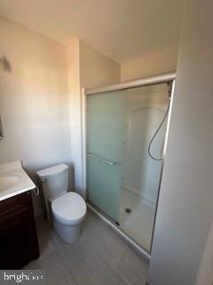 bathroom featuring toilet, vanity, and an enclosed shower