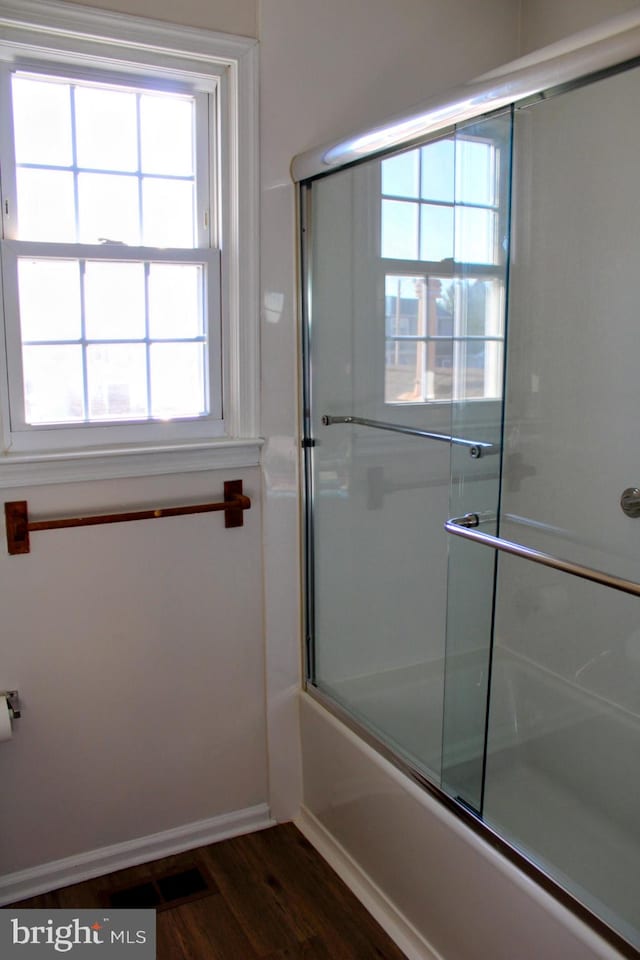 bathroom featuring enclosed tub / shower combo and hardwood / wood-style flooring