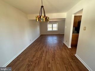 unfurnished dining area featuring dark hardwood / wood-style flooring and a chandelier