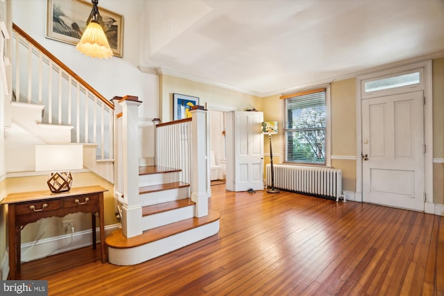 entrance foyer featuring hardwood / wood-style floors, crown molding, and radiator heating unit