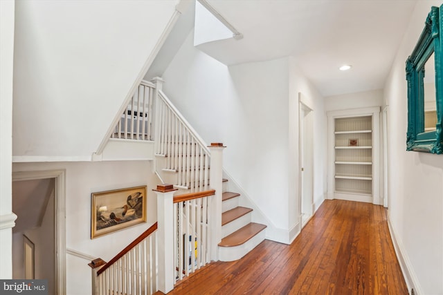 stairway with hardwood / wood-style floors and built in features