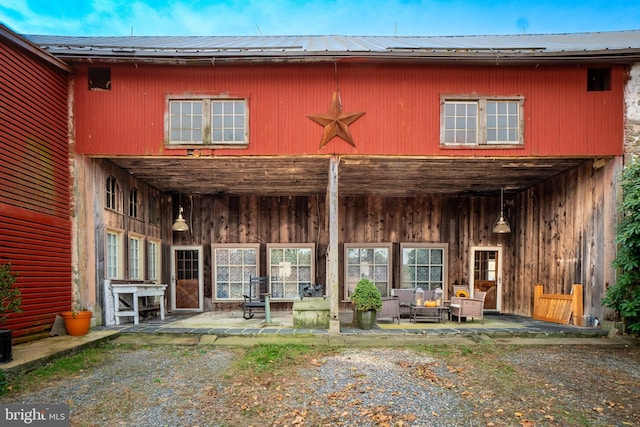 rear view of property featuring outdoor lounge area, a patio area, and metal roof