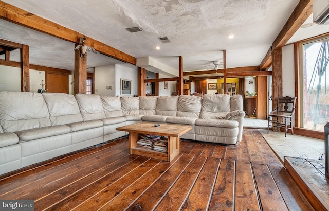 living area featuring a ceiling fan, wood-type flooring, an AC wall unit, and beam ceiling