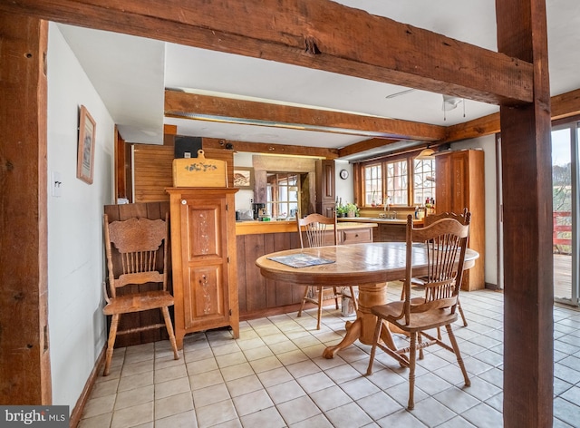 dining space featuring healthy amount of natural light, beamed ceiling, light tile patterned floors, and ceiling fan
