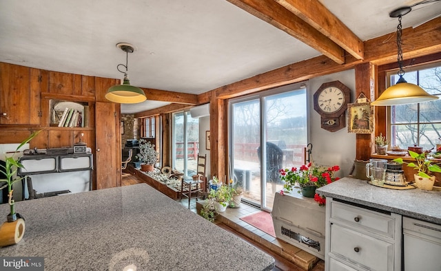 dining space featuring beamed ceiling, wood finished floors, wooden walls, and a wall mounted air conditioner