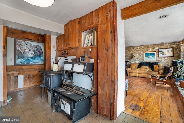 interior space with a wood stove, tile patterned flooring, and wood walls