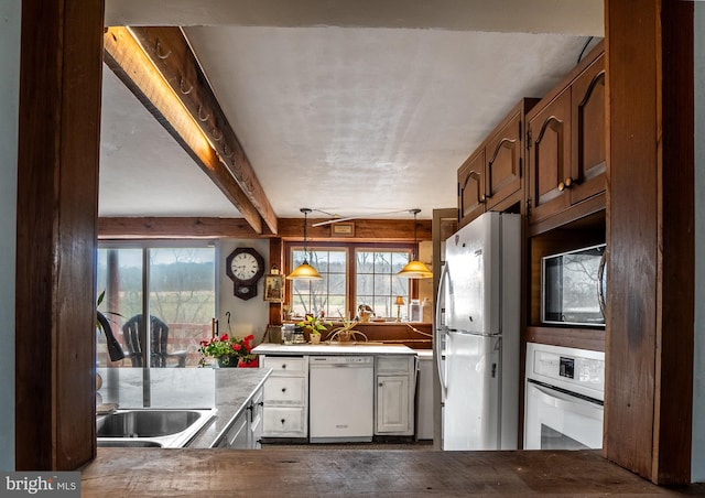 kitchen with beam ceiling, hanging light fixtures, and white appliances