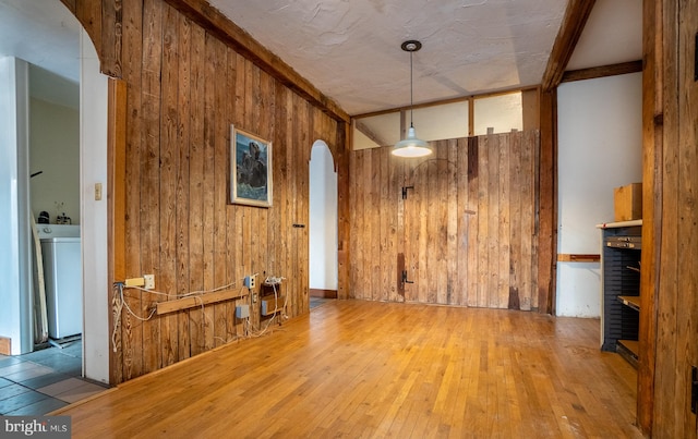 spare room with washer / clothes dryer, wooden walls, and wood-type flooring