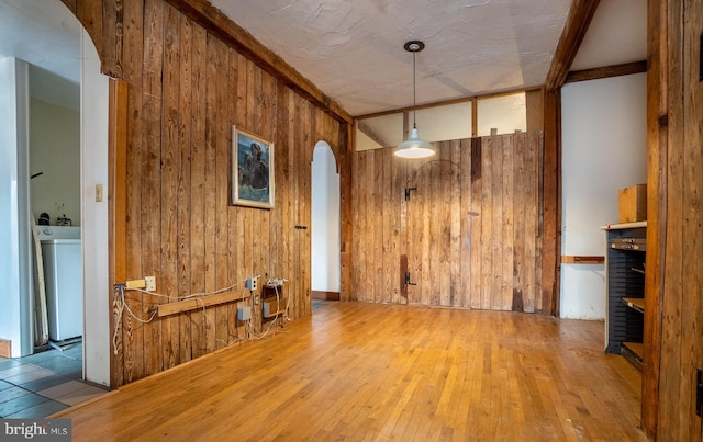 unfurnished living room with arched walkways, wood walls, and wood-type flooring