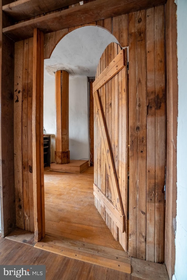 staircase with hardwood / wood-style floors and arched walkways