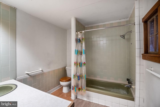 full bath with toilet, wood finished floors, tiled shower / bath, tile walls, and vanity