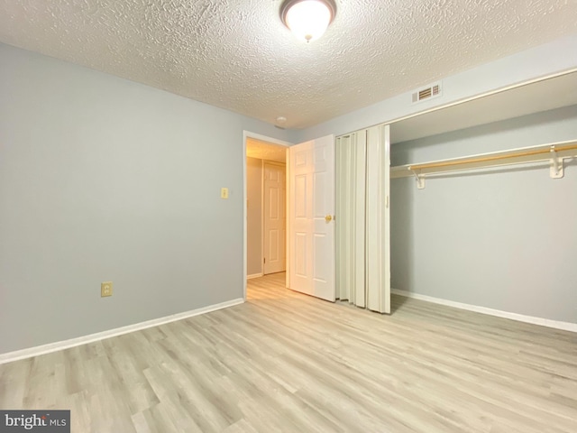 unfurnished bedroom with a closet, light wood-type flooring, and a textured ceiling