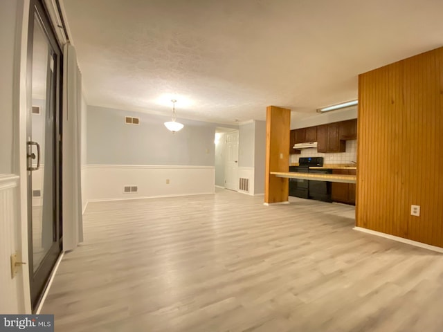 unfurnished living room featuring light hardwood / wood-style floors and wooden walls