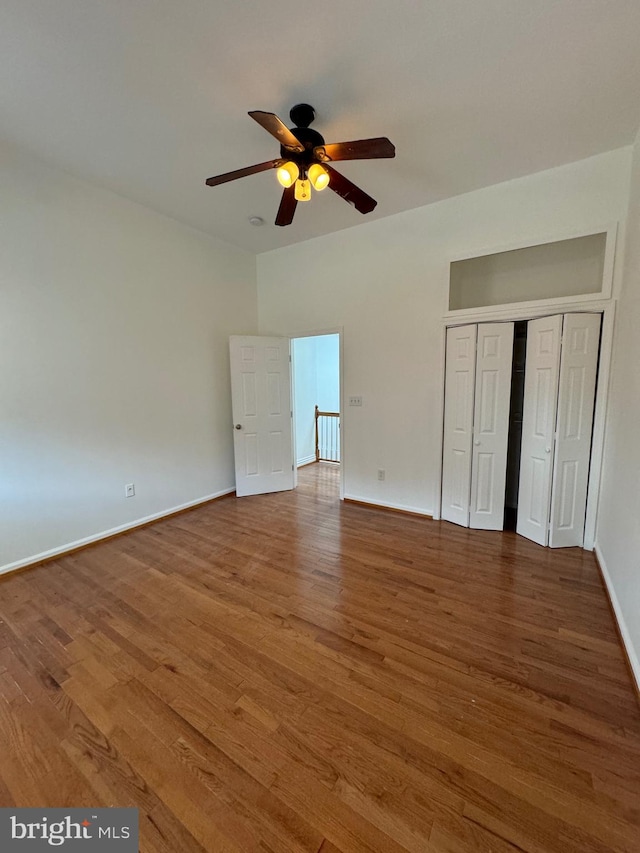 unfurnished bedroom with ceiling fan, a closet, and hardwood / wood-style flooring