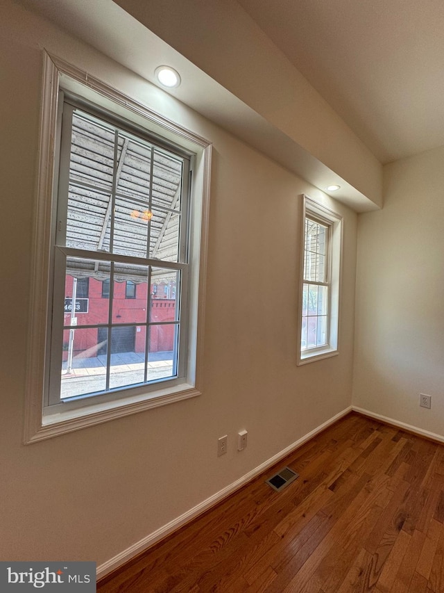 empty room featuring plenty of natural light and hardwood / wood-style flooring