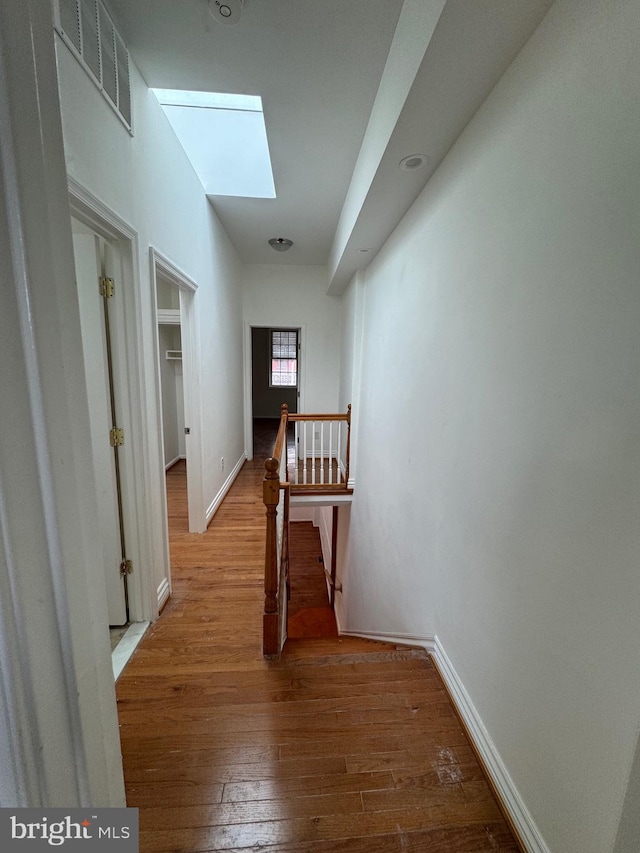 corridor with hardwood / wood-style floors and a skylight