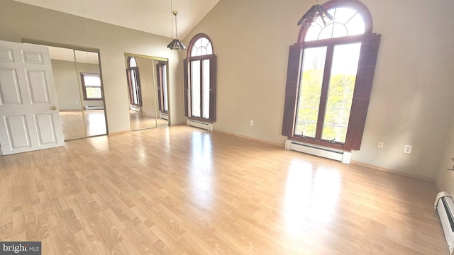 interior space with light hardwood / wood-style floors, baseboard heating, and high vaulted ceiling