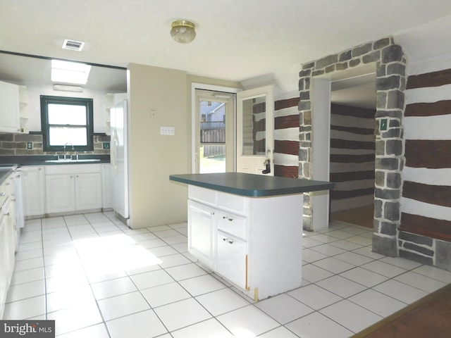 kitchen featuring white cabinets, a kitchen island, light tile patterned floors, and tasteful backsplash