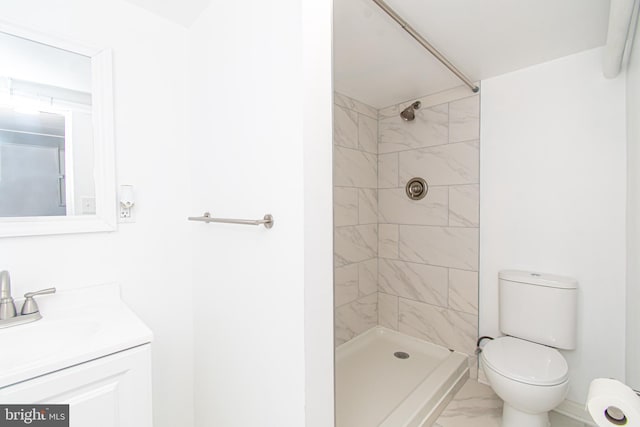 bathroom featuring toilet, vanity, and a tile shower