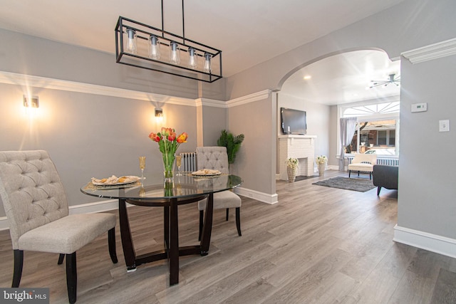 dining space with hardwood / wood-style flooring, ceiling fan, and a fireplace