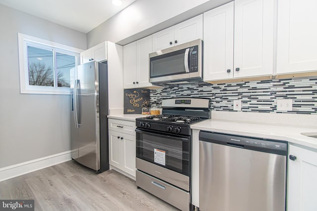 kitchen with stainless steel appliances, light hardwood / wood-style floors, white cabinets, and backsplash