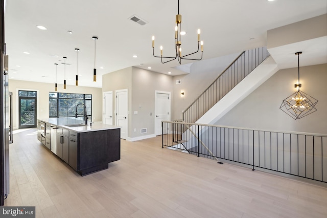 kitchen featuring sink, a spacious island, hanging light fixtures, and light hardwood / wood-style flooring