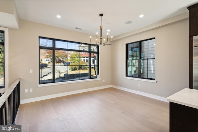 unfurnished dining area featuring an inviting chandelier and light wood-type flooring